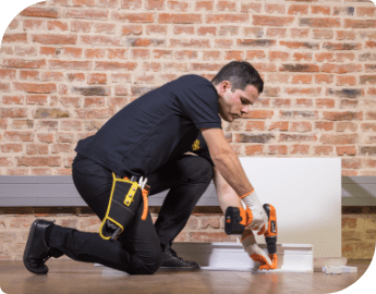 A furniture assembler on the floor working with a screwing tool