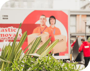 Two workers in red uniform loading a furniture in delivery van.