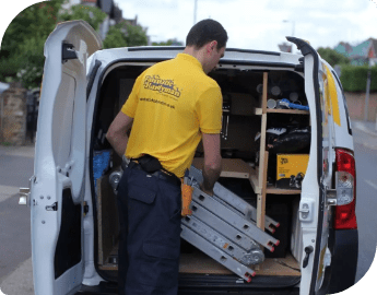 A handyman taking a ladder from the back of his van