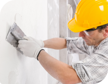 A professional wearing protective gear and using tools for wall plastering