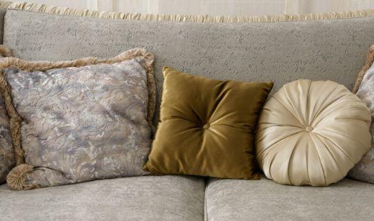 a velvet sofa with three different coloured pillows