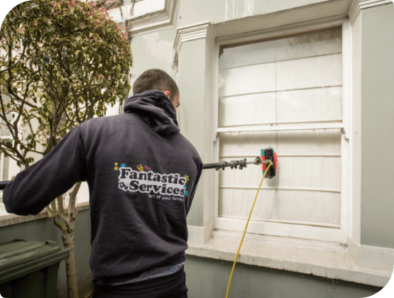 Professional in uniform cleans a window with water-fed pole