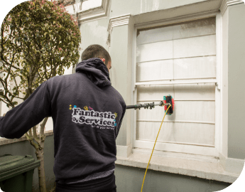 Professional in uniform cleans a window with water-fed pole