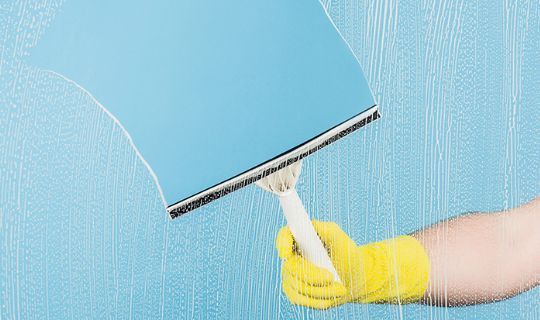 a professional removing detergent from a window with a squeegee