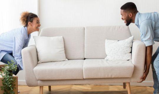 a man and a woman carrying a sofa