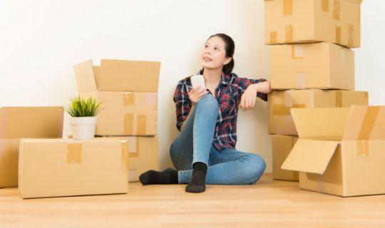 a young woman sitting and being surrounded by packing boxes