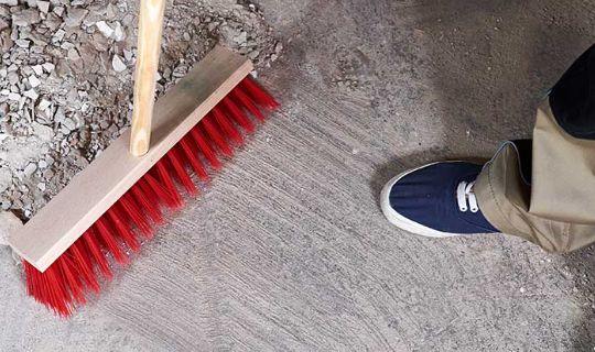 a person using a broom swiping a large amount of rubble and dust