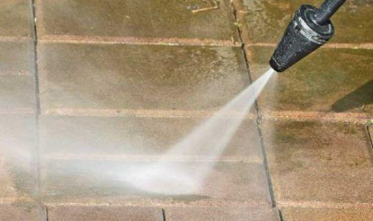 a pressure washing device spraying water onto pavement