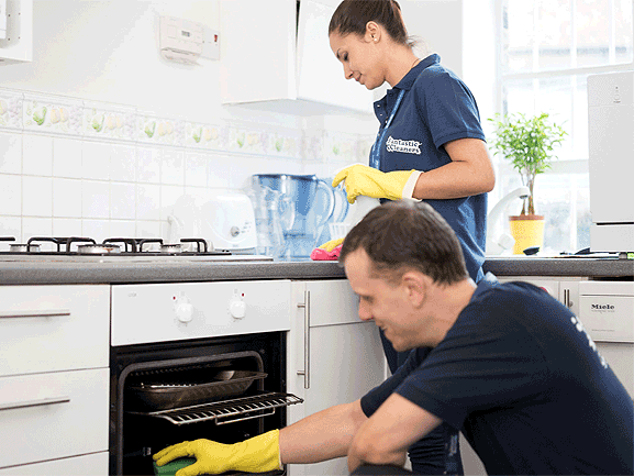 A regular cleaner in uniform who polishes a furniture.