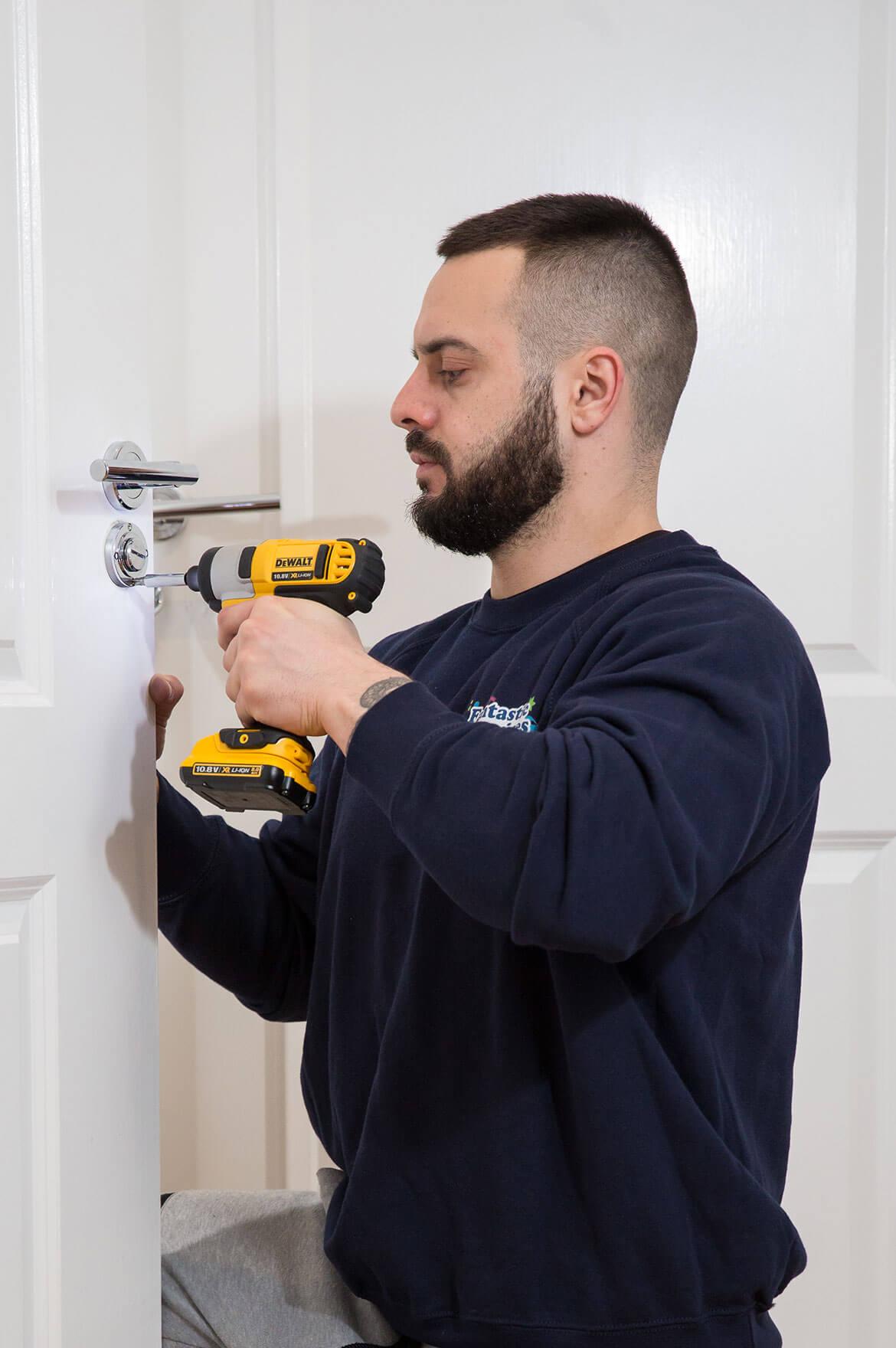 A professional emergency locksmith from Fantastic Services using a power drill to repair a door lock, showcasing expert Locksmith London services.