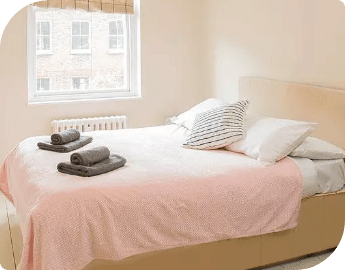 A tidy bed with pink bedding and towels on top