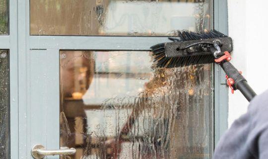 a professional using a window cleaning device spraying purified water onto a window