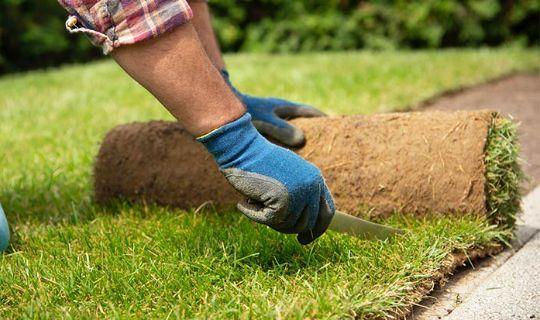 a man's hands using a knife to cut excess turf