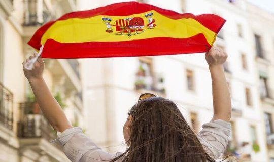 a woman holding the flag of Spain above her head