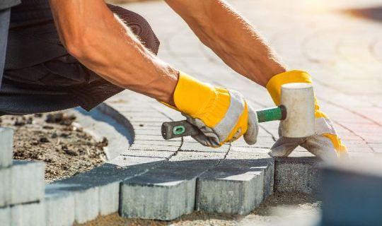 a professional using a hammer to beat in block paving slabs in the ground