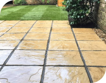 An outdoor area laid with light brown paving slabs.