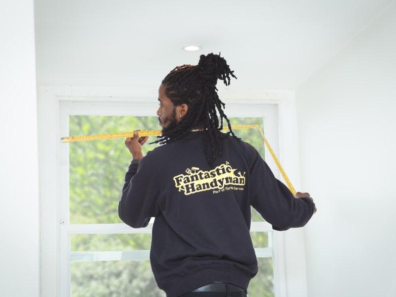 Handyman measuring a window before hanging a blind