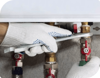 A professional's hands screwing in the pipes of a boiler