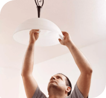 А professional electrician changing a faulty light bulb on a ceiling light