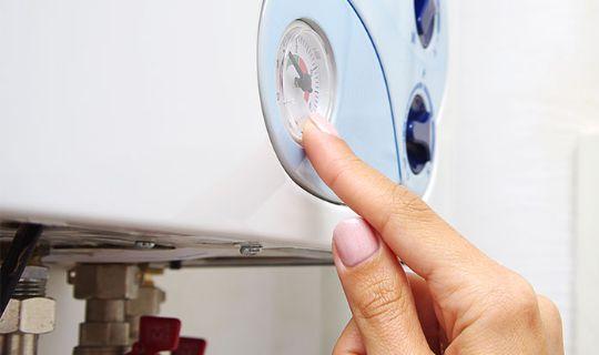 a person pointing at the pressure metre of a boiler