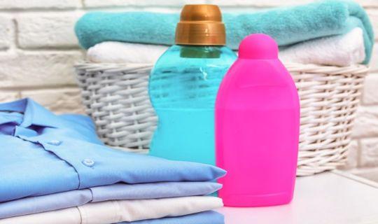 folded clothes next to a basket with blankets and a couple of detergent bottles