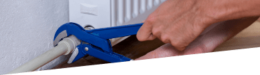 A professional's hands working with a tool on a radiator unit