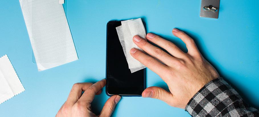 a man's hands using specialised wet wipes to disinfect a phone