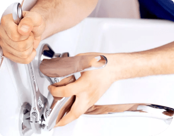 Certified plumber using a wrench to fix a sink faucet.