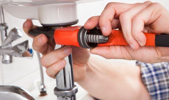 a man's hands working on fitting a pipe to a sink