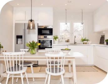 Modern kitchen interior with white furniture, stainless steel appliances, and a dining area.