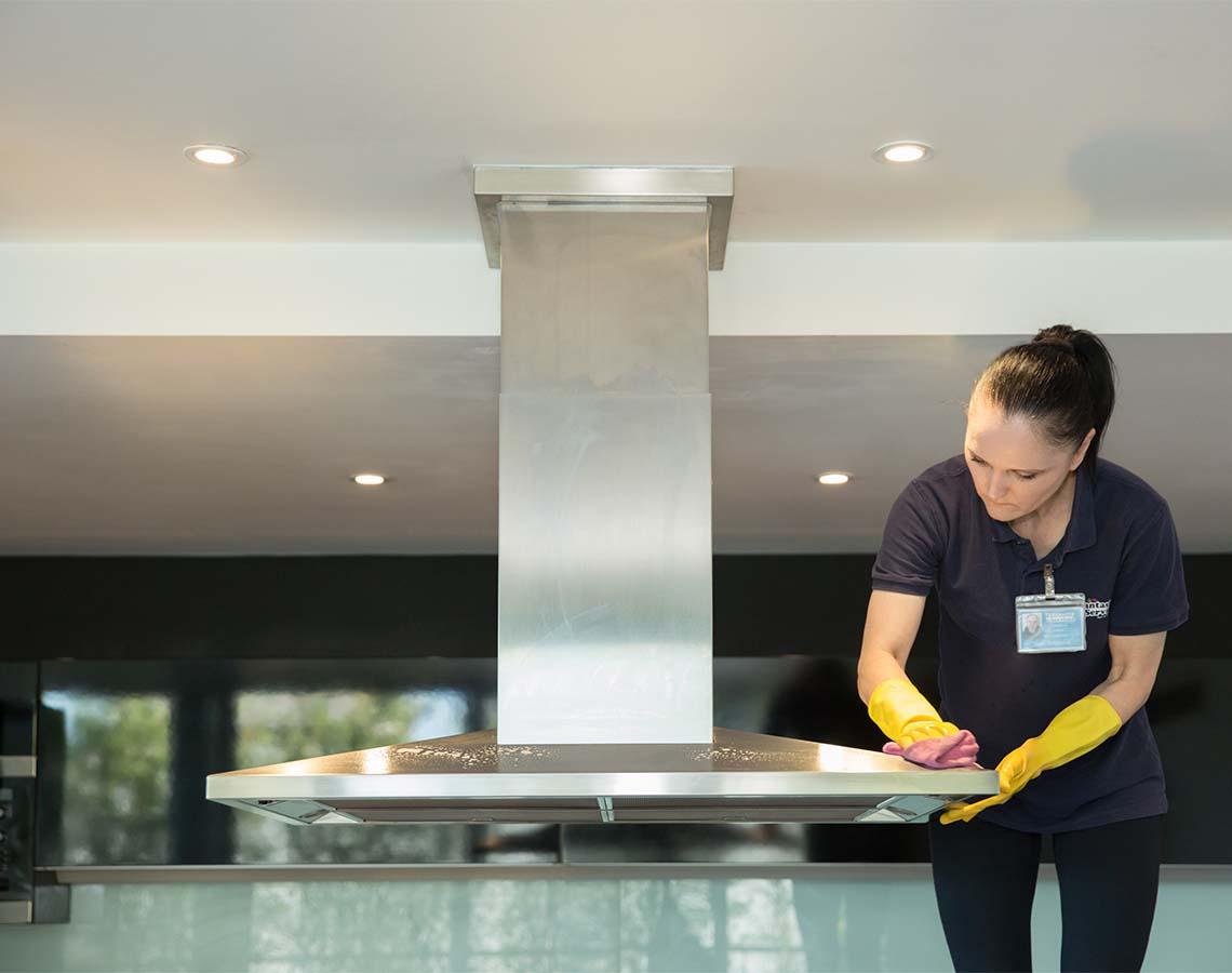 A regular cleaner in uniform who polishes a furniture.