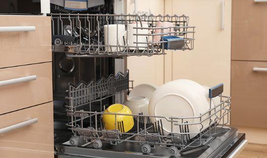 a dishwasher which is opened and filled with dishes, cups and cuttlery