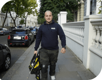 A pest controller is walking down the street, carrying professional equipment for extermination service.