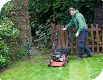 Professional gardener mowing a lawn with a red lawnmower.