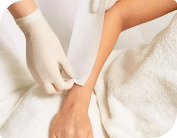 Professional applying pepper waxing strip on the hand of a woman during mobile waxing service.