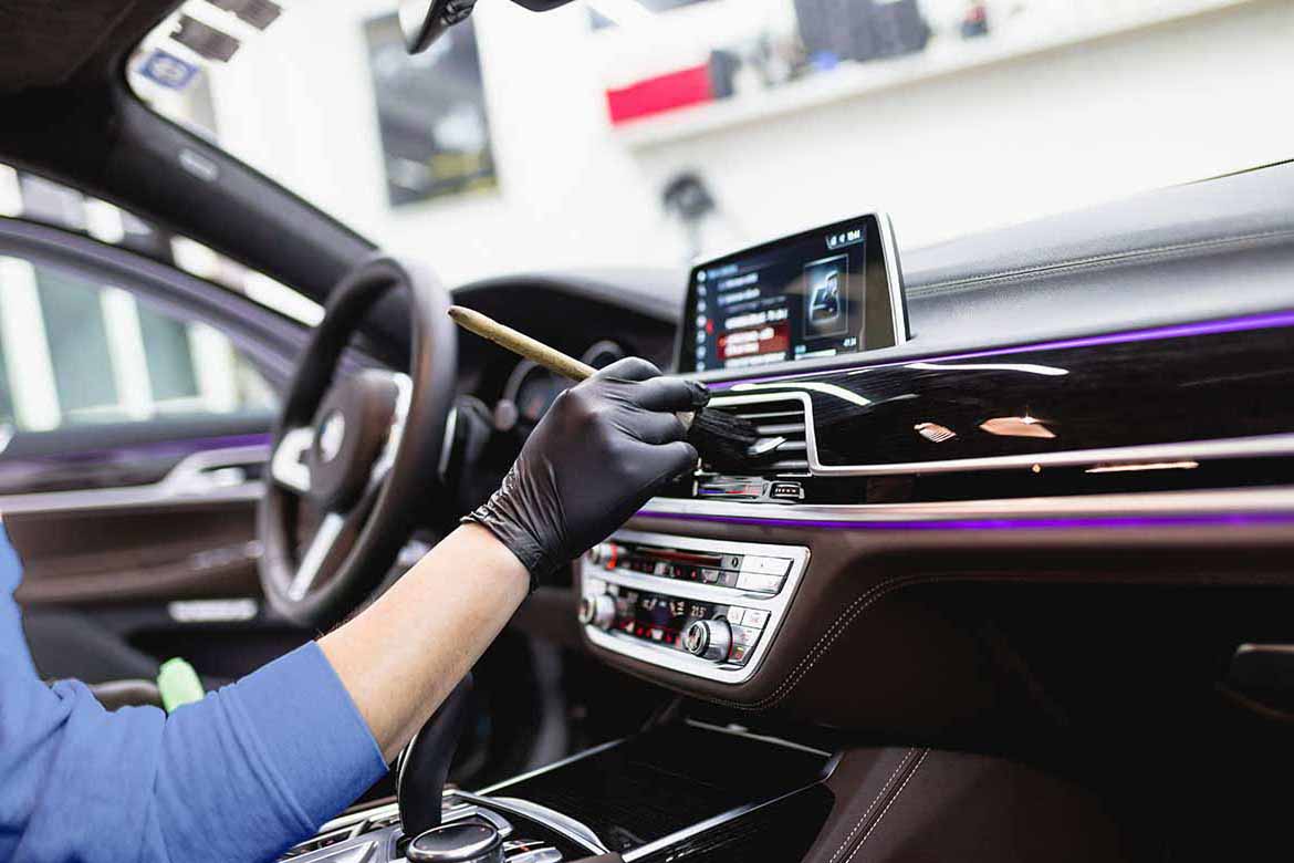 cleaner dusting the main console of a car