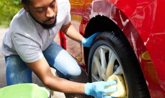 a person washing the wheels on his car