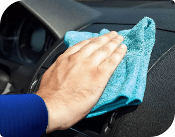 Image of a hand wiping car dashboard with blue microfiber cloth.