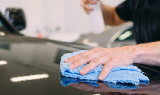 a man applying ceramic coating to a black coloured vehicle's hood