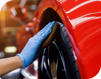 Close-up of the hand of a professional who cleans the rims and tyres of a car during car valeting service.