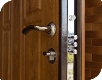 Close-up of a wooden door with a metal handle, deadbolt, and security latch system.