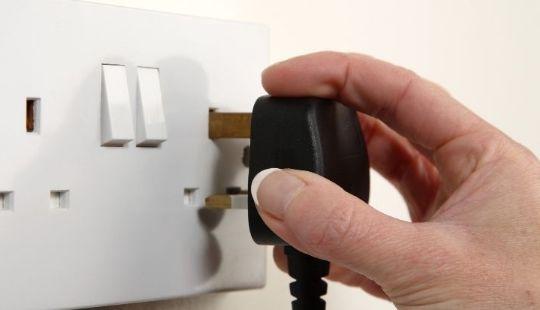 hand putting plug in electric socket