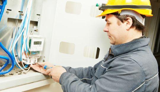 an electrician wearing protective gear and working on a fuse box