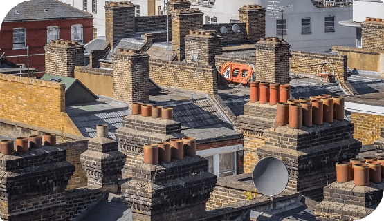 Rooftop view of multiple brick chimneys in an urban area.