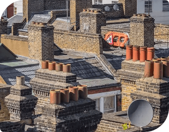 Rooftop view of multiple brick chimneys in an urban area.