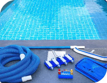 Swimming pool with equipment for pool cleaning on the side, including a hose, brushes, and chemical bottles.