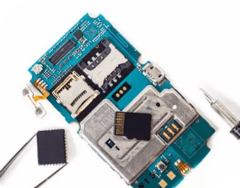 Disassembled smartphone motherboard with components and tools on a white background.