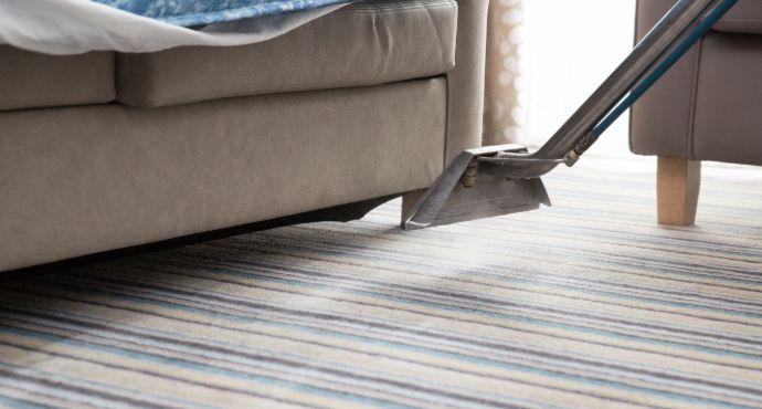 The image shows a clean dim gray couch and a clean rug in a living room. The rug is white with a geometric pattern.