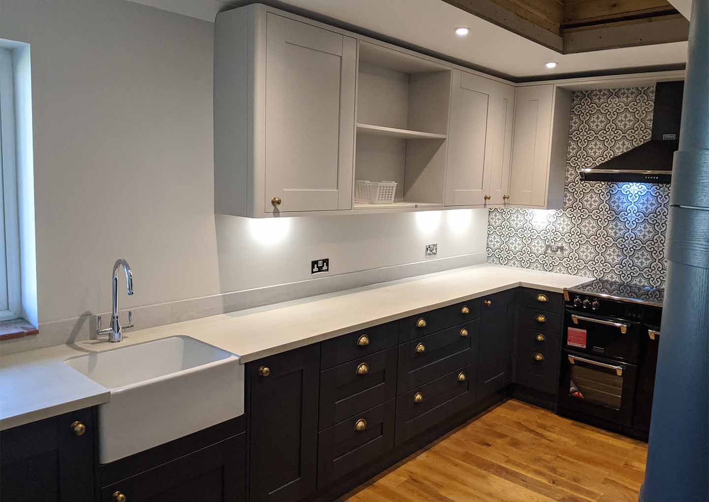 Modern kitchen with white cabinets, patterned backsplash, and wooden floor.