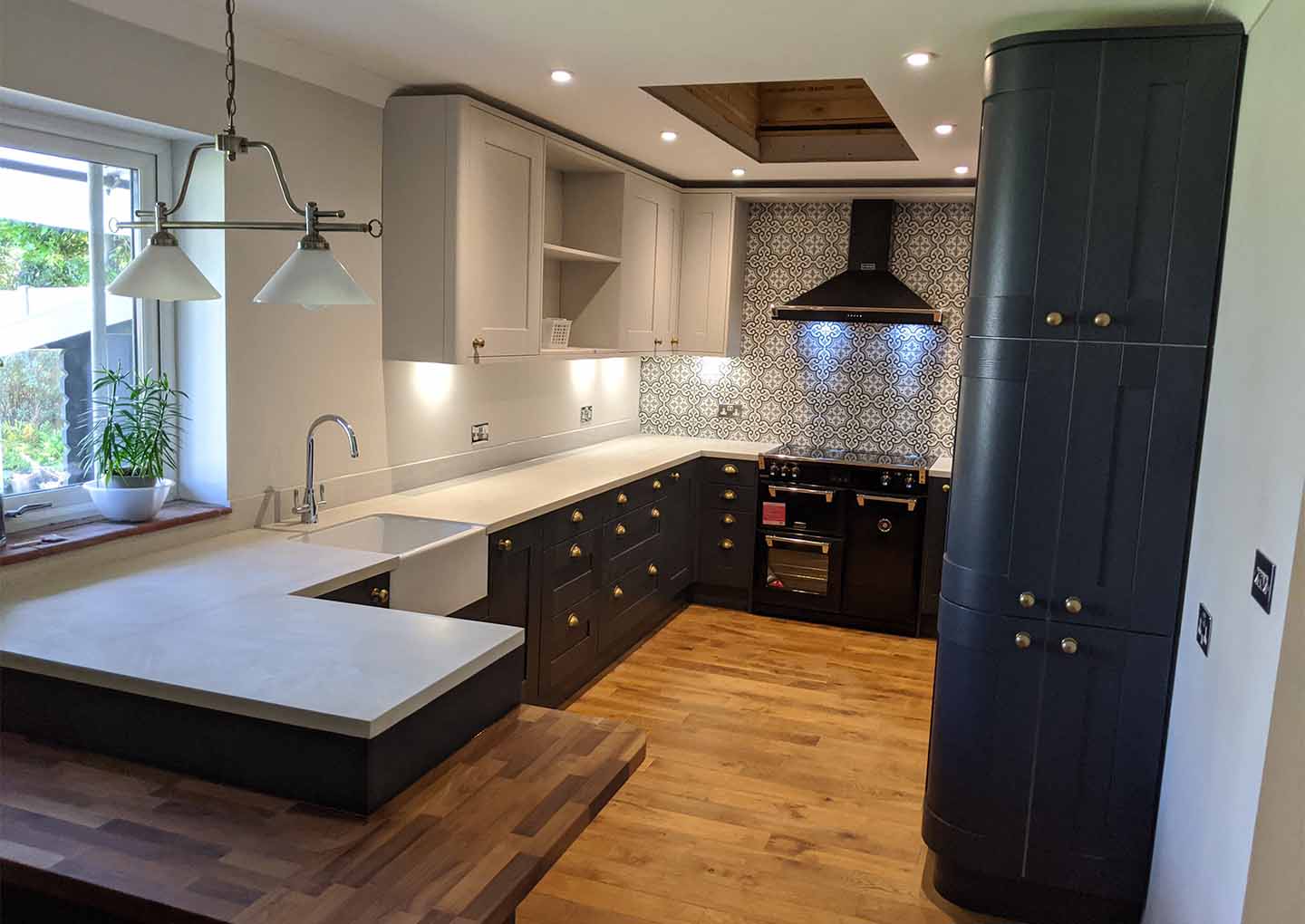 Picture of a kitchen with grey cabinets, white countertops, a patterned backsplash, and a wooden floor.